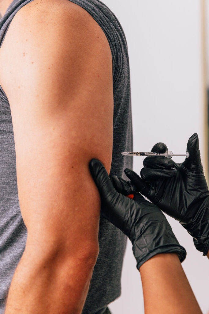A provider at The Pip RX administers a patient's NAD+ injections, often used in a weight loss plan in Overland Park. Wearing surgical gloves, the provider prepares to place the NAD+ injection in the patient's upper arm using an ultra-fine syringe.